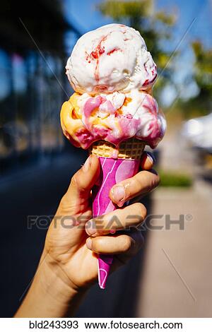 Stock Image - Hand of Mixed Race girl holding melting ice cream cone. Fotosearch