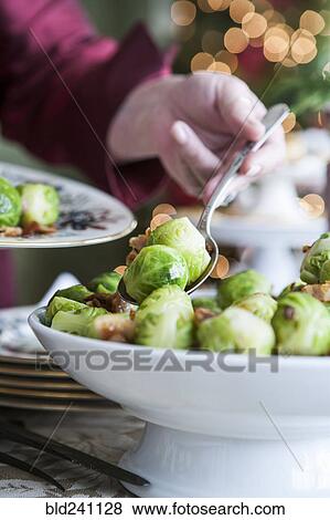 Stock Photo - Hand serving brussels sprouts with spoon. Fotosearch