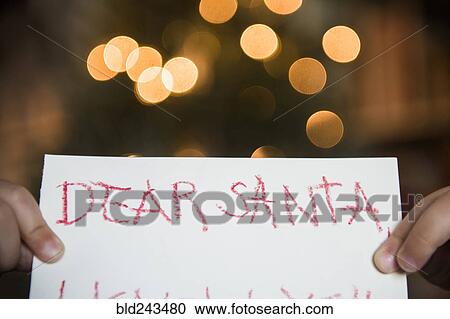Stock Image - Hands of Caucasian girl holding dear Santa letter. Fotosearch