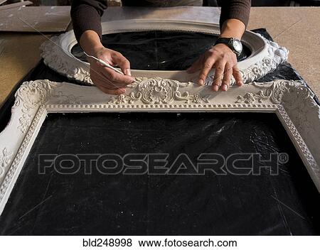 Stock Photo - Hands of Caucasian man detailing picture frame. Fotosearch
