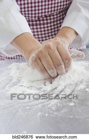 Stock Photograph - Hands of Hispanic woman kneading dough in flour. Fotosearch