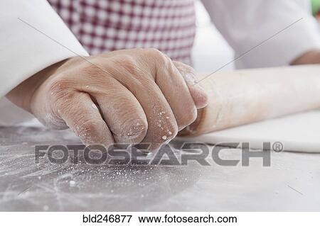 Stock Photo - Hands of Hispanic woman using rolling pin on dough. Fotosearch