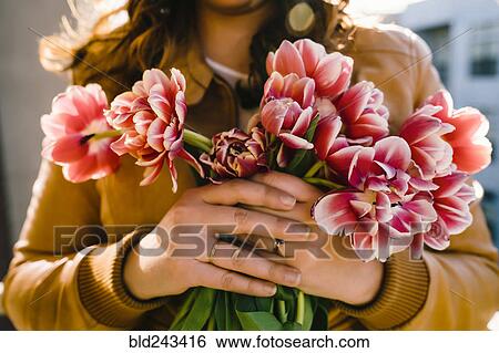 Stock Photograph - Hands of Mixed Race woman holding flowers. Fotosearch