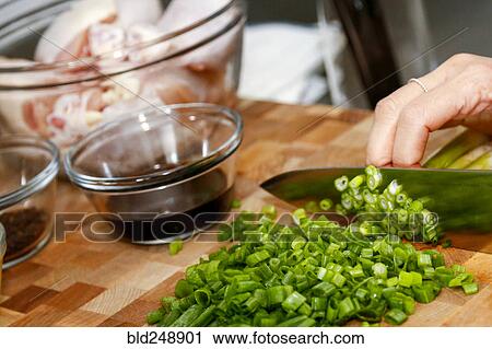 Stock Image - Hands of woman chopping onions on cutting board. Fotosearch