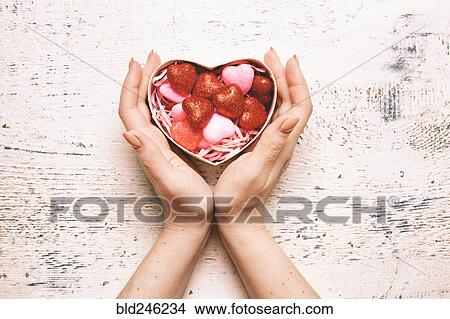 Picture - Hands of woman cupping valentine gift box. Fotosearch
