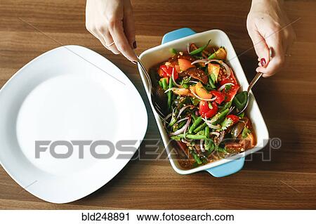 Stock Image - Hands of woman mixing salad. Fotosearch