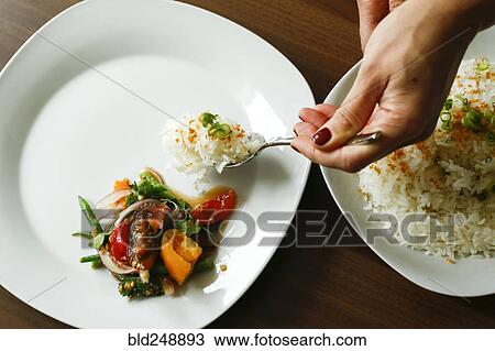 Stock Image - Hands of woman serving rice. Fotosearch