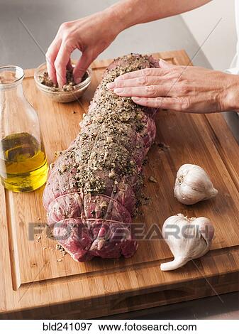 Stock Photo - Hands rubbing garlic and pepper onto tenderloin. Fotosearch
