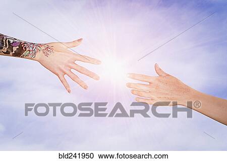 Stock Image - Hands with tattoos and freckles reaching in sky. Fotosearch