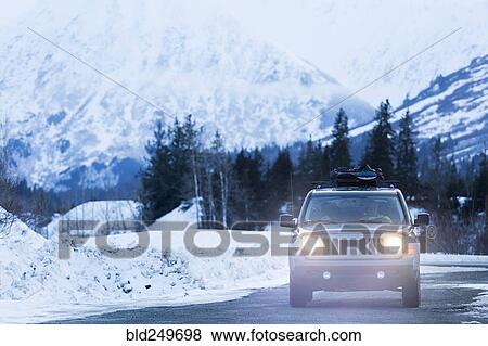 Stock Photo - Headlights shining from car driving in winter. Fotosearch