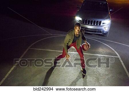 Headlights shining on Black man playing basketball View Large Photo Image Picture - Headlights shining on Black man playing basketball. Fotosearch