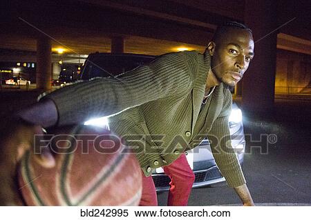 Stock Photography - Headlights shining on Black man playing basketball. Fotosearch