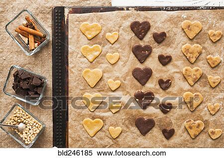 Stock Photography - Heart-shape cookies on baking sheet near ingredients. Fotosearch