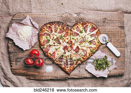 Heart-shaped pizza and ingredients on cutting board View Large Photo Image Stock Photo - Heart-shaped pizza and ingredients on cutting board. Fotosearch