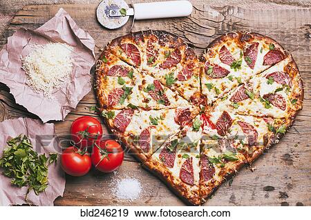 Heart-shaped pizza and ingredients on cutting board View Large Photo Image Stock Photo - Heart-shaped pizza and ingredients on cutting board. Fotosearch