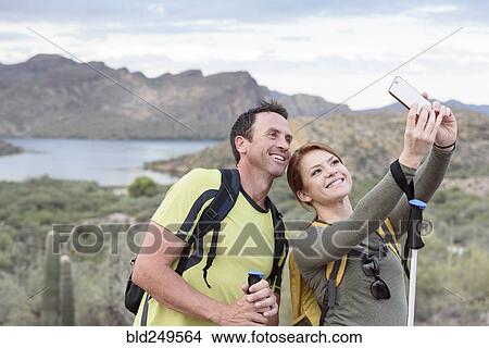 Picture - Hikers posing for cell phone selfie in desert. Fotosearch