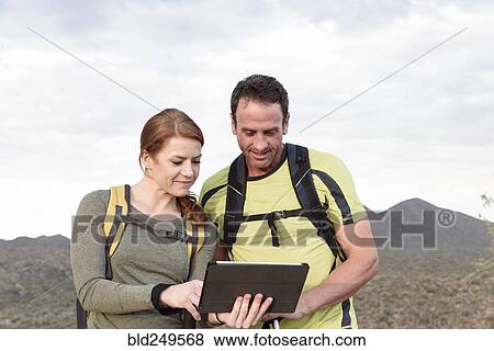 Stock Photo - Hikers using digital tablet in desert. Fotosearch
