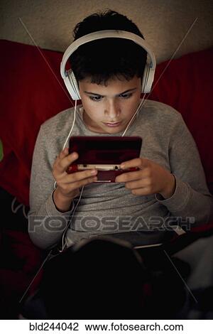 Hispanic boy listening to cell phone with headphones View Large Photo Image Stock Image - Hispanic boy listening to cell phone with headphones. Fotosearch