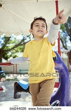 Hispanic boy on carousel at playground View Large Photo Image Stock Photograph - Hispanic boy on carousel at playground. Fotosearch
