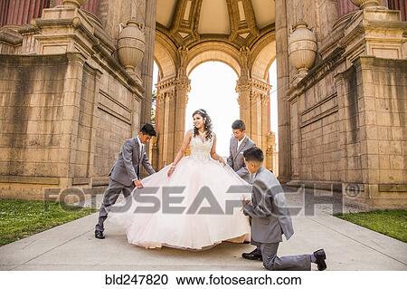 Stock Image - Hispanic boys holding skirt of girl. Fotosearch