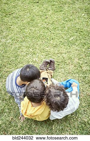 Stock Image - Hispanic boys playing with cell phone. Fotosearch