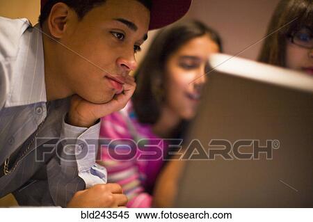 Stock Photography - Hispanic brother and sisters using laptop. Fotosearch