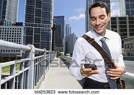 Hispanic businessman texting on cell phone in city View Large Photo Image Stock Image - Hispanic businessman texting on cell phone in city. Fotosearch