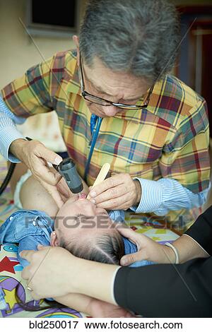 Stock Photo - Hispanic doctor examining mouth of girl with Down Syndrome. Fotosearch