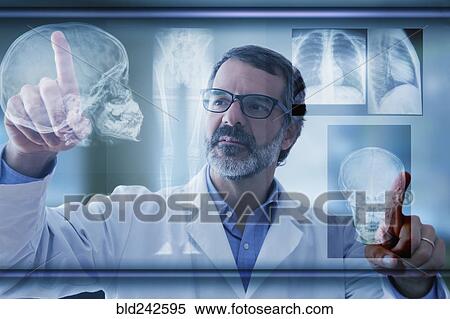 Stock Photography - Hispanic doctor examining x-rays on virtual screen. Fotosearch