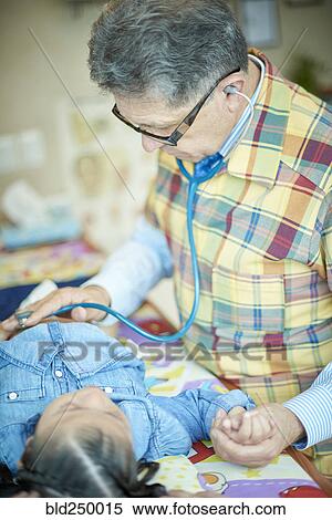 Hispanic doctor listening to chest of girl with stethoscope View Large Photo Image Stock Photography - Hispanic doctor listening to chest of girl with stethoscope. Fotosearch