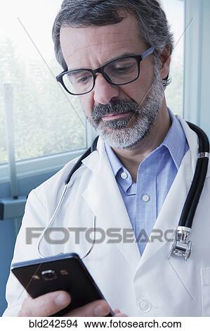 Hispanic doctor texting on cell phone View Large Photo Image Picture - Hispanic doctor texting on cell phone. Fotosearch