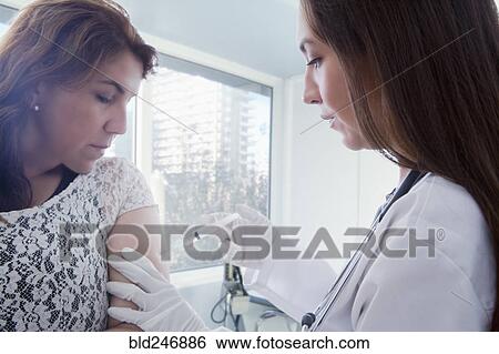 Hispanic doctor vaccinating patient View Large Photo Image Stock Photograph - Hispanic doctor vaccinating patient. Fotosearch