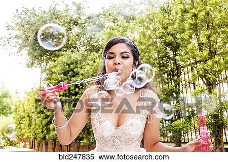 Hispanic girl wearing gown blowing bubbles View Large Photo Image Stock Photography - Hispanic girl wearing gown blowing bubbles. Fotosearch