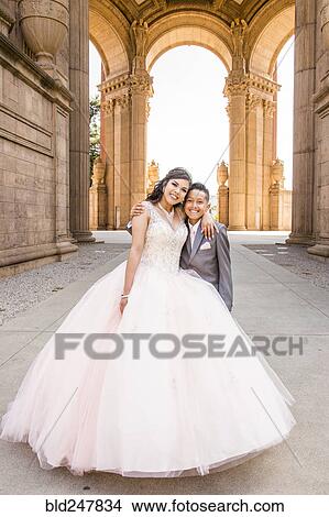 Picture - Hispanic girl wearing gown hugging boy. Fotosearch