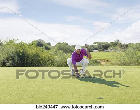 Stock Photo - Hispanic golfer crouching on golf course. Fotosearch