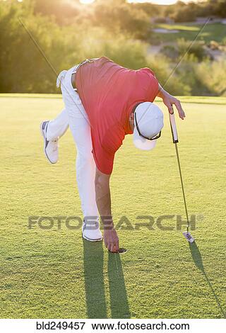 Hispanic golfer reaching into hole on golf course View Large Photo Image Stock Photo - Hispanic golfer reaching into hole on golf course. Fotosearch