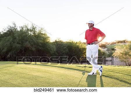 Stock Image - Hispanic golfer waiting on golf course. Fotosearch