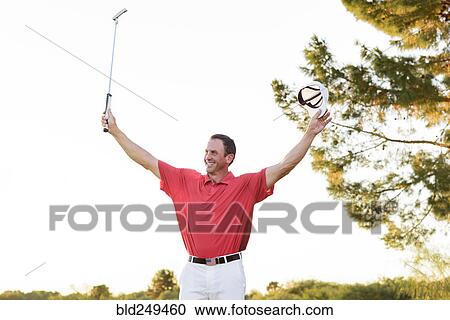 Stock Image - Hispanic golfer waving on golf course. Fotosearch