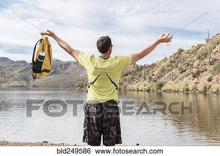Hispanic man celebrating with arms raised at lake View Large Photo Image Stock Photograph - Hispanic man celebrating with arms raised at lake. Fotosearch
