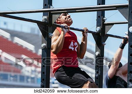 Hispanic man doing chin-ups outdoors View Large Photo Image Stock Photo - Hispanic man doing chin-ups outdoors. Fotosearch