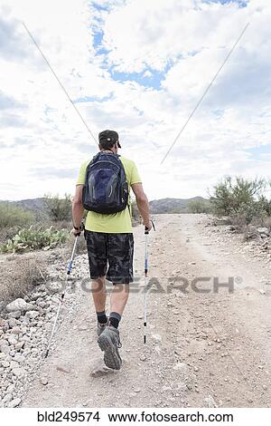 Picture - Hispanic man hiking on rocky path in desert. Fotosearch