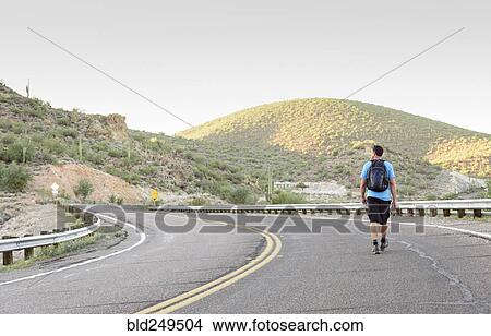 Picture - Hispanic man hiking on winding street. Fotosearch