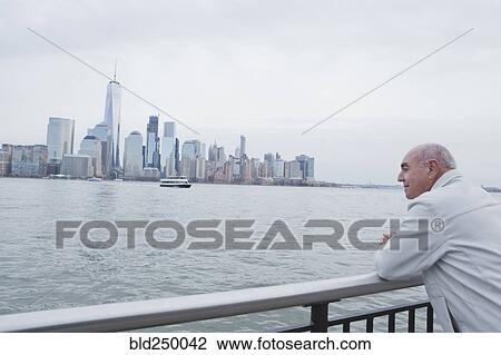 Hispanic man leaning on railing admiring scenic view of city View Large Photo Image Stock Image - Hispanic man leaning on railing admiring scenic view of city. Fotosearch