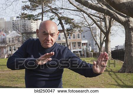 Stock Photo - Hispanic man performing exercise in park. Fotosearch