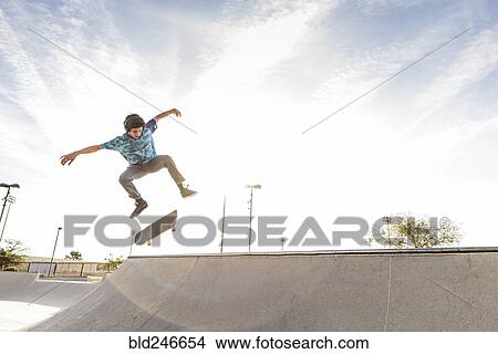 Picture - Hispanic man performing mid-air trick on skateboard. Fotosearch