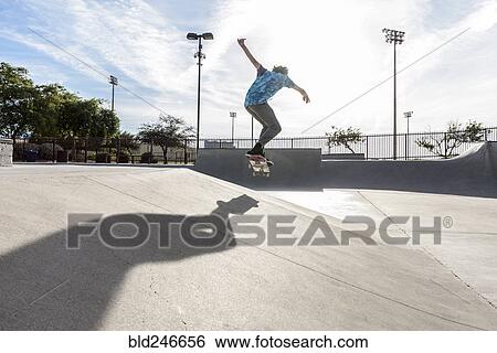Stock Photograph - Hispanic man performing mid-air trick on skateboard. Fotosearch