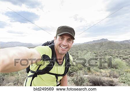 Stock Photo - Hispanic man posing for selfie in desert. Fotosearch