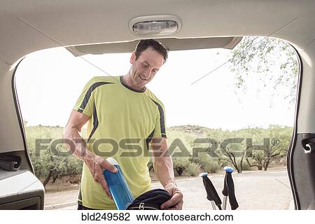 Hispanic man pulling water bottle from backpack in car View Large Photo Image Stock Image - Hispanic man pulling water bottle from backpack in car. Fotosearch
