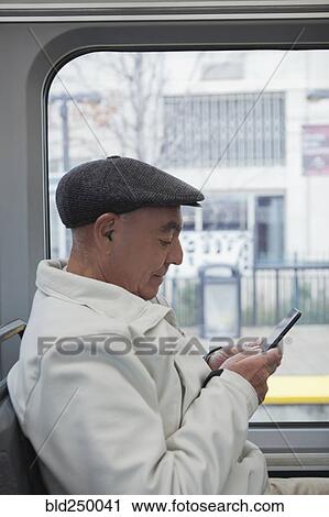 Hispanic man sitting on train texting on cell phone View Large Photo Image Stock Image - Hispanic man sitting on train texting on cell phone. Fotosearch