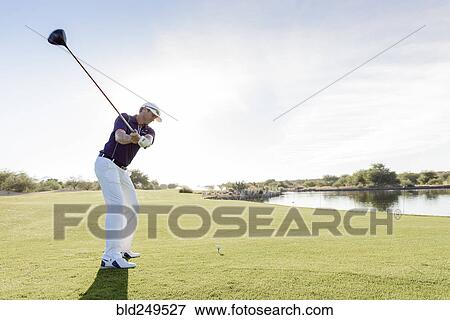 Stock Photo - Hispanic man teeing off on golf course. Fotosearch